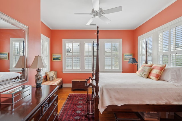 bedroom with baseboards, multiple windows, ornamental molding, and wood finished floors