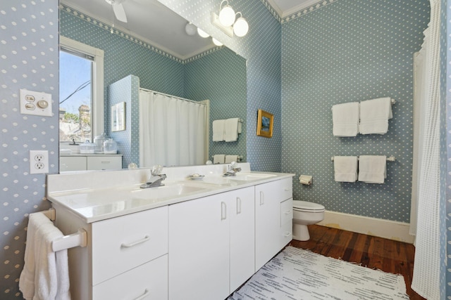 bathroom featuring a sink, toilet, wallpapered walls, and wood finished floors