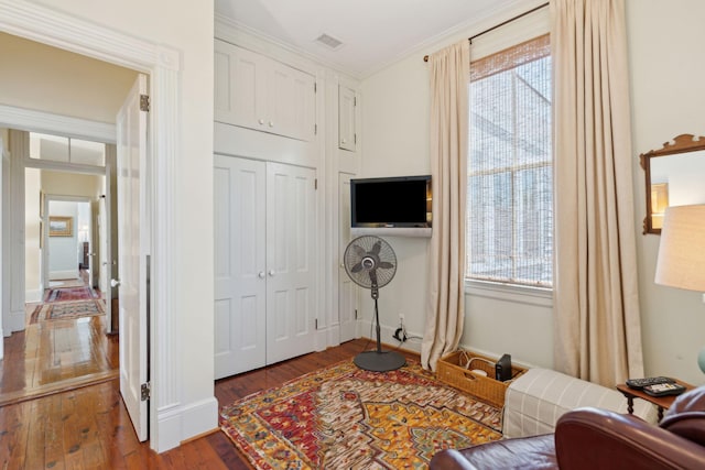 interior space featuring crown molding, visible vents, baseboards, and hardwood / wood-style floors
