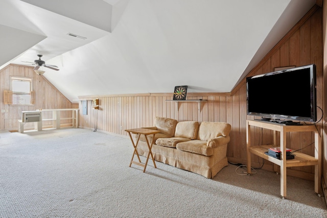 carpeted living room featuring vaulted ceiling, wood walls, a ceiling fan, and visible vents