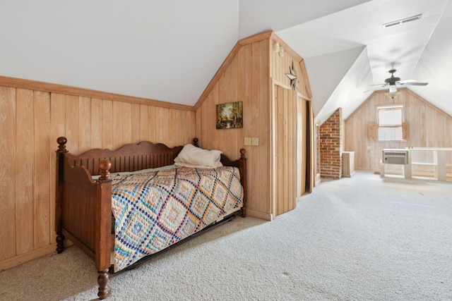 carpeted bedroom with a ceiling fan, visible vents, lofted ceiling, and wooden walls