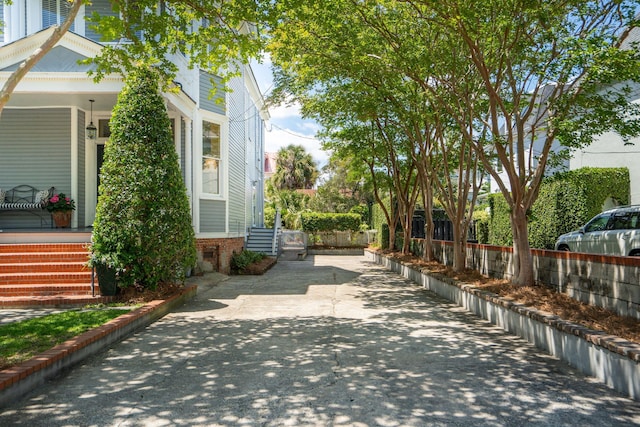 view of home's exterior featuring a porch, brick siding, and fence