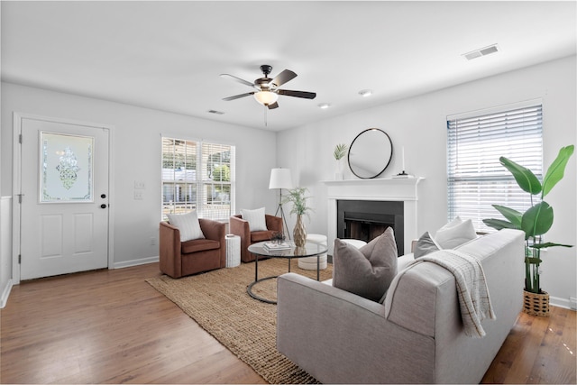 living room featuring visible vents, a ceiling fan, wood finished floors, a fireplace, and baseboards