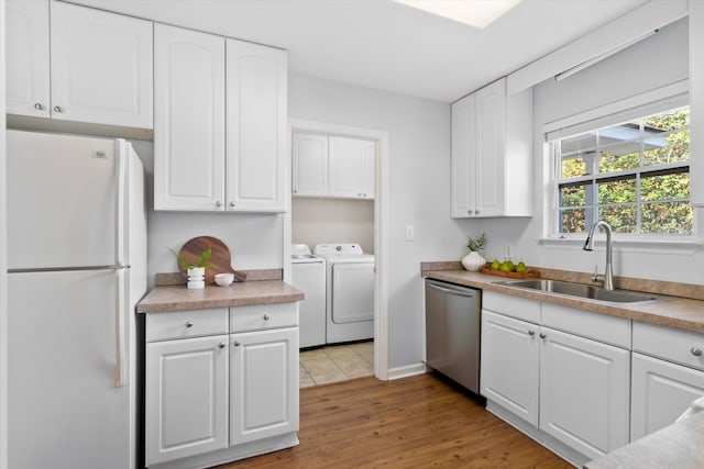 kitchen with separate washer and dryer, freestanding refrigerator, a sink, white cabinets, and dishwasher