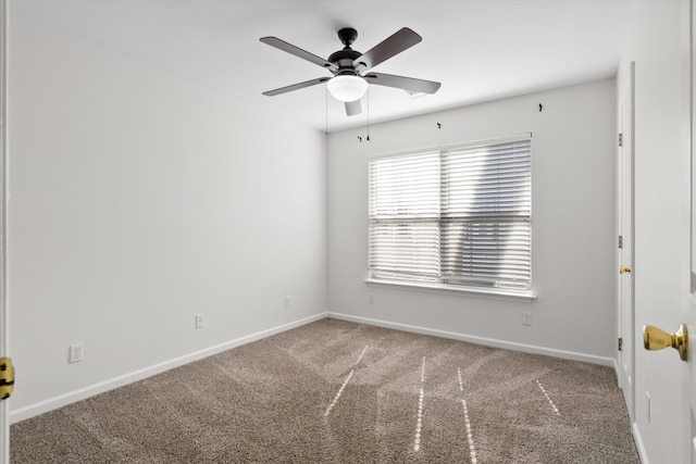 carpeted spare room featuring baseboards and a ceiling fan