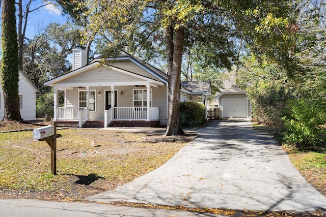 bungalow-style home featuring an outbuilding, driveway, a porch, a garage, and a chimney