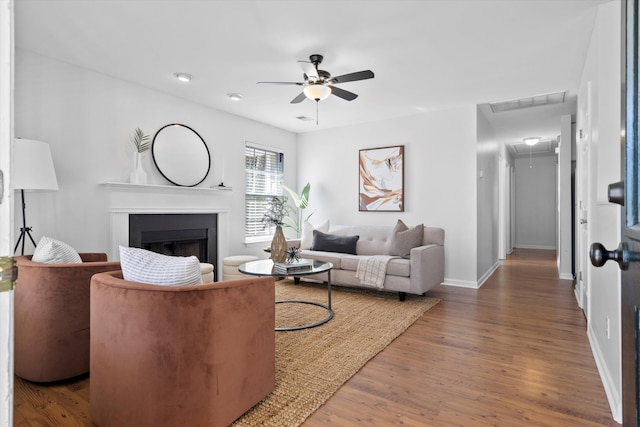 living room featuring visible vents, wood finished floors, a fireplace, baseboards, and attic access