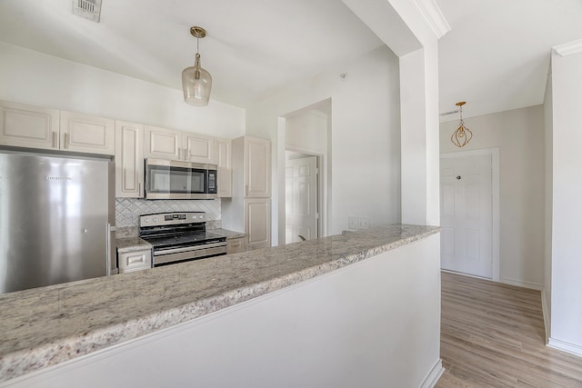 130 River Landing Dr Unit 2310, Daniel Island, SC 29492 - kitchen featuring stainless steel appliances, backsplash, hanging light fixtures, light wood-type flooring, and cream cabinets