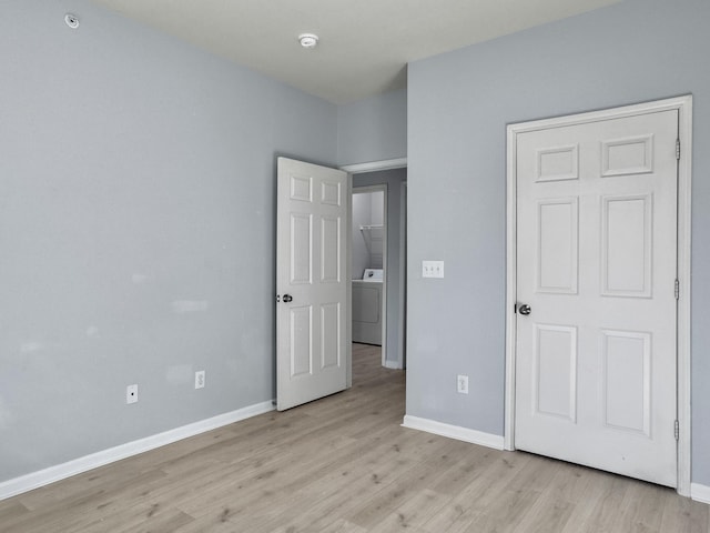 unfurnished bedroom featuring washer / clothes dryer and light wood-type flooring