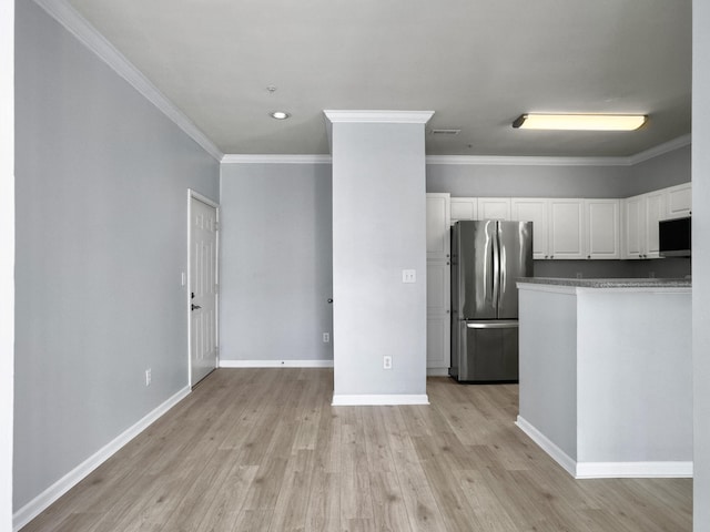 kitchen with light hardwood / wood-style floors, ornamental molding, stainless steel refrigerator, and white cabinets