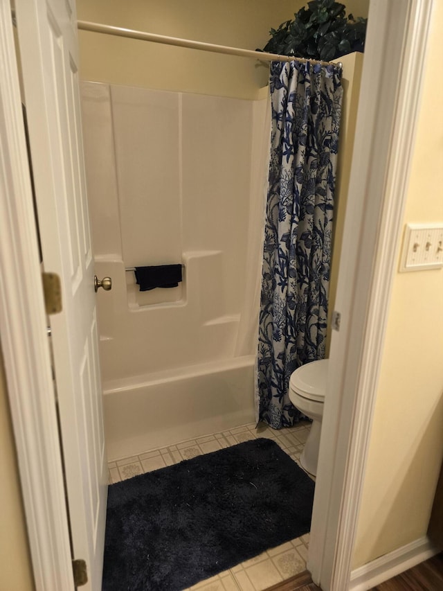 bathroom with tile patterned flooring, toilet, and shower / tub combo with curtain