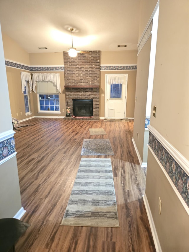 unfurnished living room featuring dark hardwood / wood-style flooring and a brick fireplace