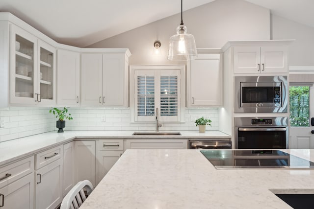 kitchen with white cabinetry, appliances with stainless steel finishes, lofted ceiling, and sink