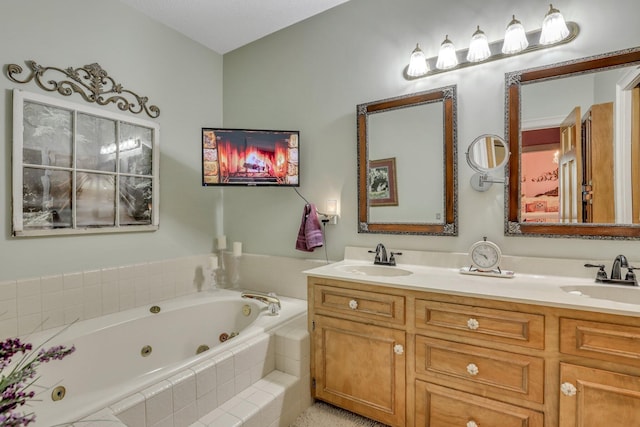 bathroom with a textured ceiling, tiled tub, and vanity