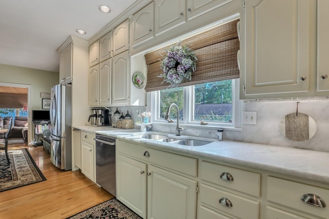 kitchen with stainless steel appliances, light wood-type flooring, sink, and decorative backsplash