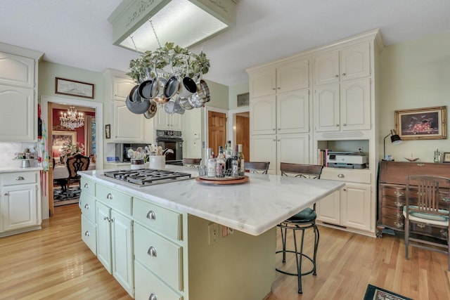 kitchen with a kitchen island, a chandelier, stainless steel gas stovetop, black oven, and a kitchen bar