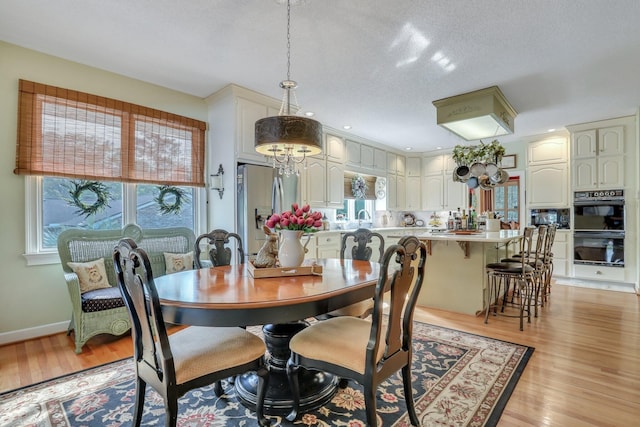 dining room with a notable chandelier, light hardwood / wood-style floors, a healthy amount of sunlight, and sink