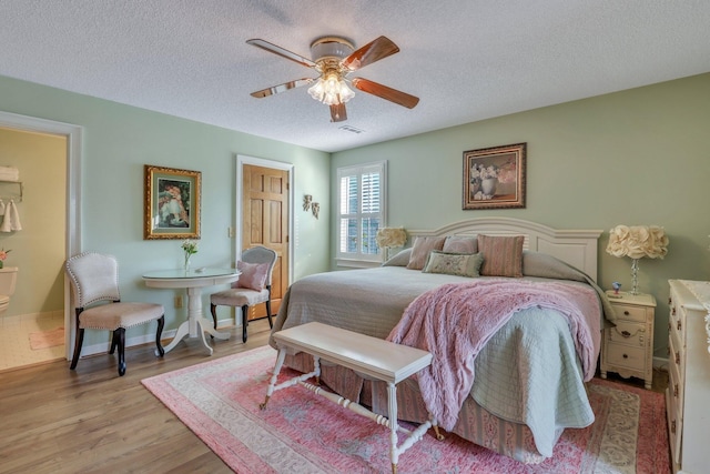 bedroom with light wood-type flooring, a textured ceiling, and ceiling fan