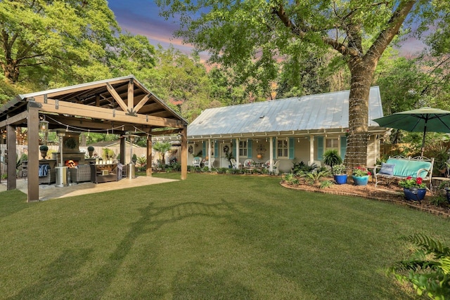 back house at dusk with a gazebo, a lawn, and a patio