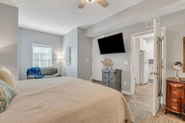 bedroom featuring ceiling fan, white refrigerator, and light wood-type flooring