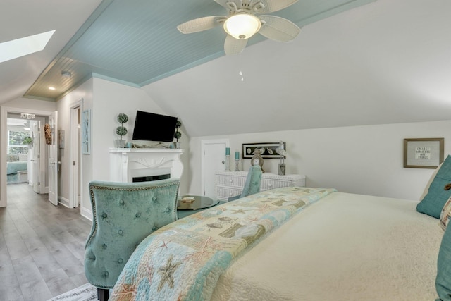 bedroom with wood-type flooring, ceiling fan, and lofted ceiling with skylight