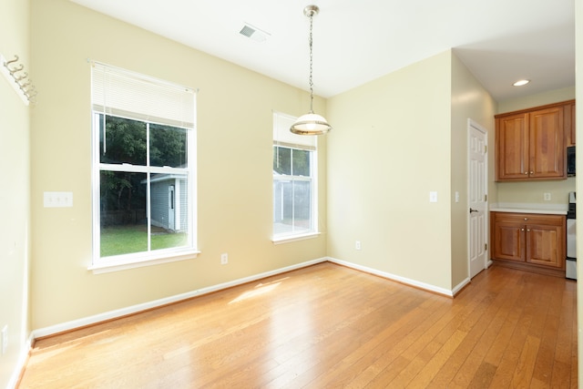 unfurnished dining area featuring light wood-type flooring and a wealth of natural light