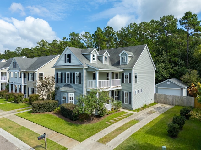 view of front of house with a front yard, a balcony, a garage, and an outdoor structure