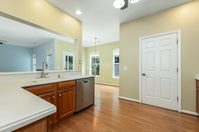 kitchen featuring dishwasher, light hardwood / wood-style floors, hanging light fixtures, and sink