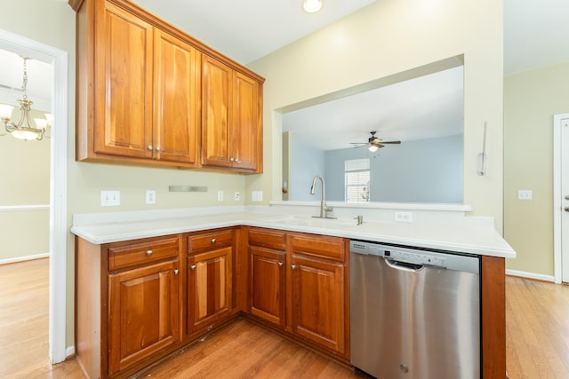 kitchen with kitchen peninsula, stainless steel dishwasher, ceiling fan with notable chandelier, sink, and light hardwood / wood-style floors