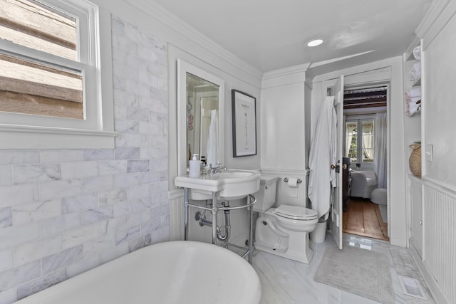 176 Smith St, Charleston, SC 29403 - ensuite bathroom with a freestanding tub, marble look tile flooring, ornamental molding, and wainscoting