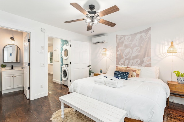 bedroom with a wall mounted air conditioner, dark hardwood / wood-style flooring, ceiling fan, stacked washer / dryer, and connected bathroom