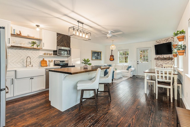 kitchen with white cabinets, ceiling fan, a center island, and appliances with stainless steel finishes