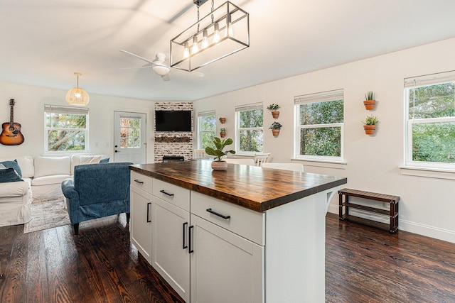 kitchen with pendant lighting, wood counters, white cabinets, ceiling fan, and a kitchen island