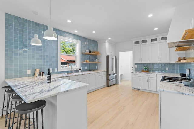 kitchen with high end refrigerator, light wood-style flooring, a peninsula, open shelves, and a sink