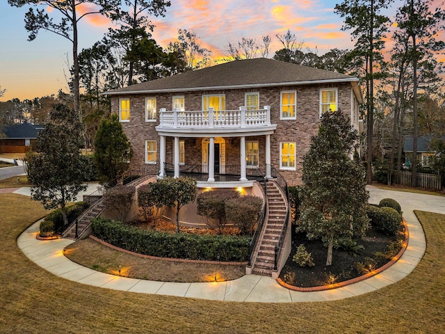 colonial house featuring a lawn, covered porch, and a balcony