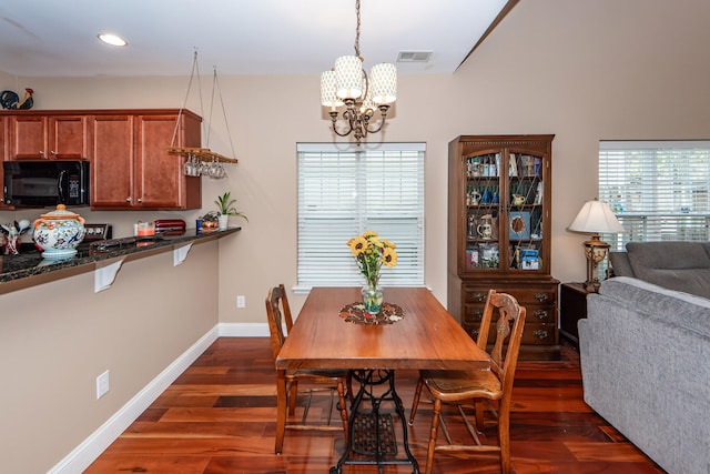 dining space featuring dark wood-type flooring and an inviting chandelier