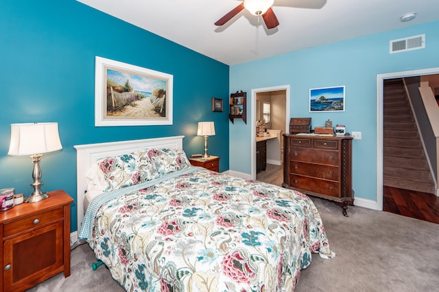 bedroom with ensuite bathroom, light carpet, and ceiling fan