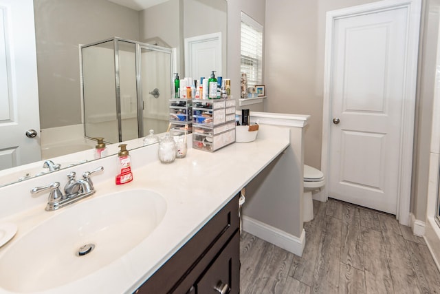 bathroom with vanity, toilet, a shower with shower door, and hardwood / wood-style floors