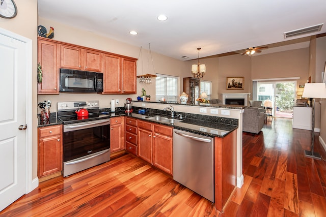 kitchen with kitchen peninsula, hardwood / wood-style floors, stainless steel appliances, and ceiling fan with notable chandelier