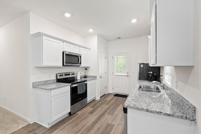 309 Sedona Dr, Summerville, SC 29486 - kitchen with stainless steel appliances, a sink, light wood-style floors, white cabinets, and light stone counters