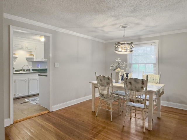 dining area featuring an inviting chandelier, crown molding, baseboards, and wood finished floors