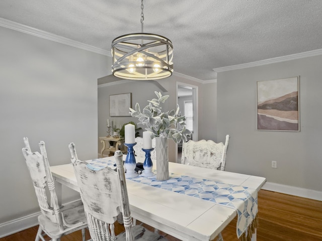 dining room featuring a textured ceiling, ornamental molding, wood finished floors, and baseboards