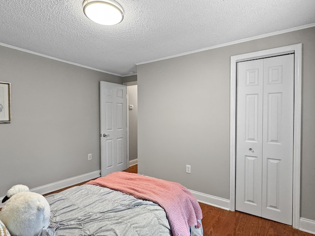 bedroom featuring baseboards, a closet, wood finished floors, and crown molding