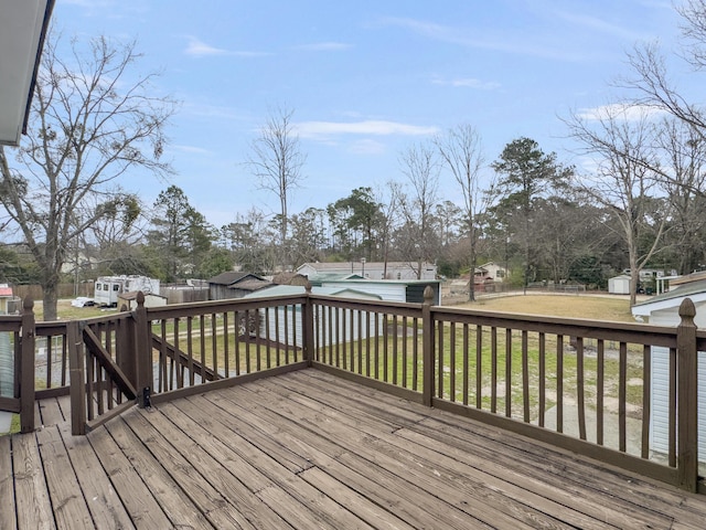 wooden terrace featuring an outbuilding, a lawn, and a storage shed