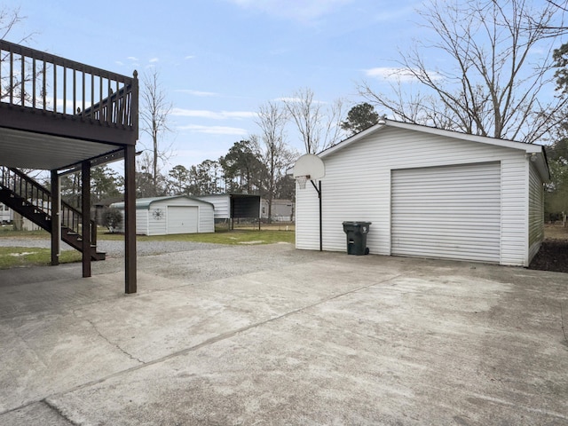 exterior space with an outbuilding, a deck, a detached garage, stairs, and driveway