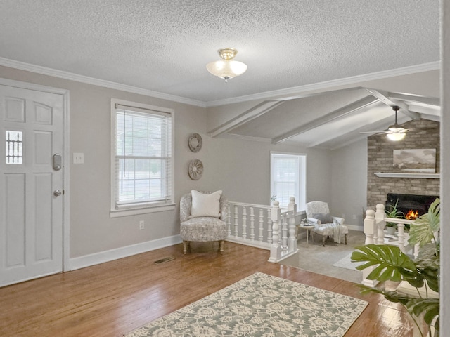 entrance foyer featuring a brick fireplace, plenty of natural light, and wood finished floors