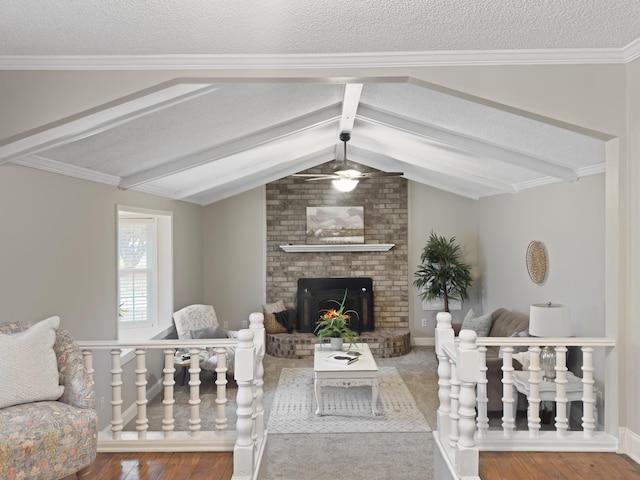 living area featuring lofted ceiling with beams, a textured ceiling, a fireplace, and wood finished floors