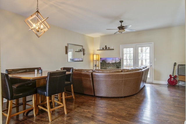 living room with dark hardwood / wood-style flooring and ceiling fan with notable chandelier