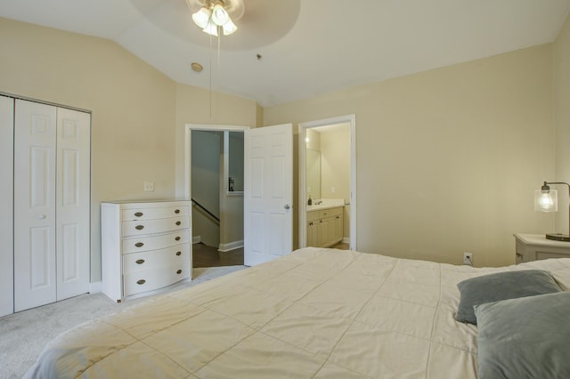 bedroom with a closet, vaulted ceiling, ensuite bath, ceiling fan, and carpet flooring