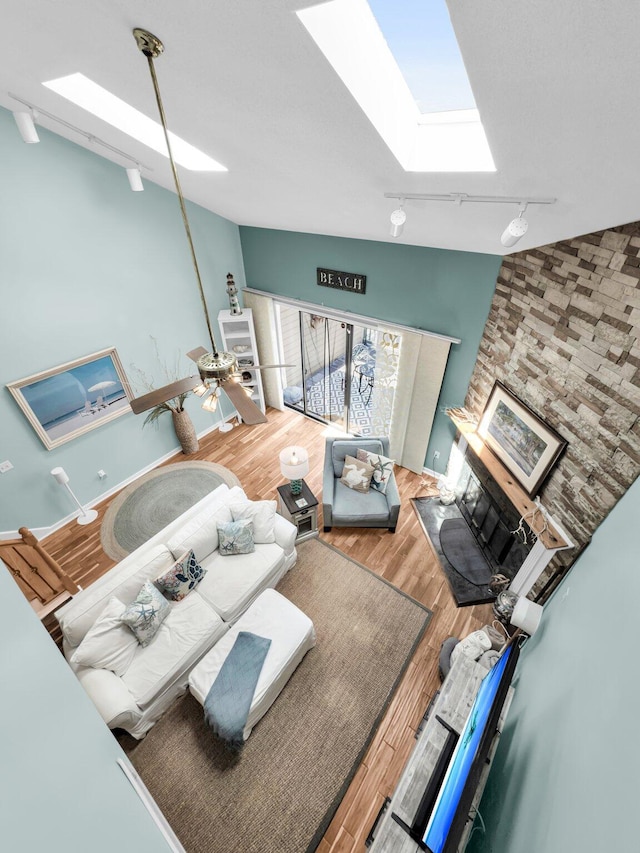 166 River Breeze Dr, Charleston, SC 29407 - living room with a skylight, a glass covered fireplace, wood finished floors, rail lighting, and vaulted ceiling